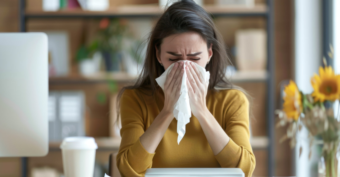 Employee sneezing at their desk